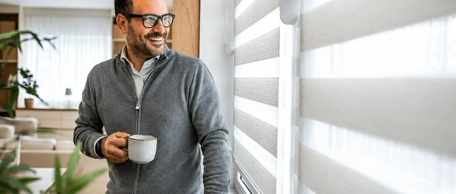 Man smiling with morning coffee by a sunlit window